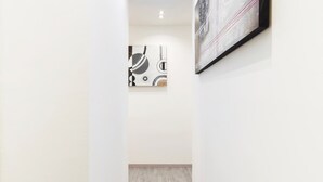 A hallway with a wooden floor and white walls. There are two artworks on the walls. - B&B di Paolo S. (Rome)