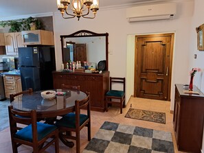 A dining area with a round table, chairs, a chandelier, and a wooden cabinet with a mirror. - Three Bedrooms Apartment Nile view Maadi (Maadi)