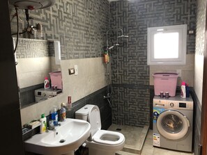 A bathroom with a sink, toilet, shower, and a washing machine. - Three Bedrooms Apartment Nile view Maadi (Maadi)