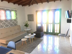 Uma sala de estar com um sofá, uma mesa de centro e uma TV sobre um suporte.