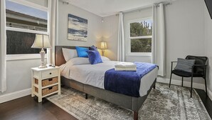 Een slaapkamer met een bed, nachtlampjes, een nachtkastje, een stoel en uitzicht op de omgeving.