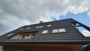 Un edificio moderno con tetto spiovente, numerose finestre e un balcone ben visibile.