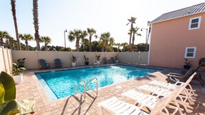 A swimming pool with a tiled deck, surrounded by palm trees and a fence. - A Few Steps to the Beach, at this Hidden Gem in Panama City Beach Fl. Unit-6 (Panama City Beach)