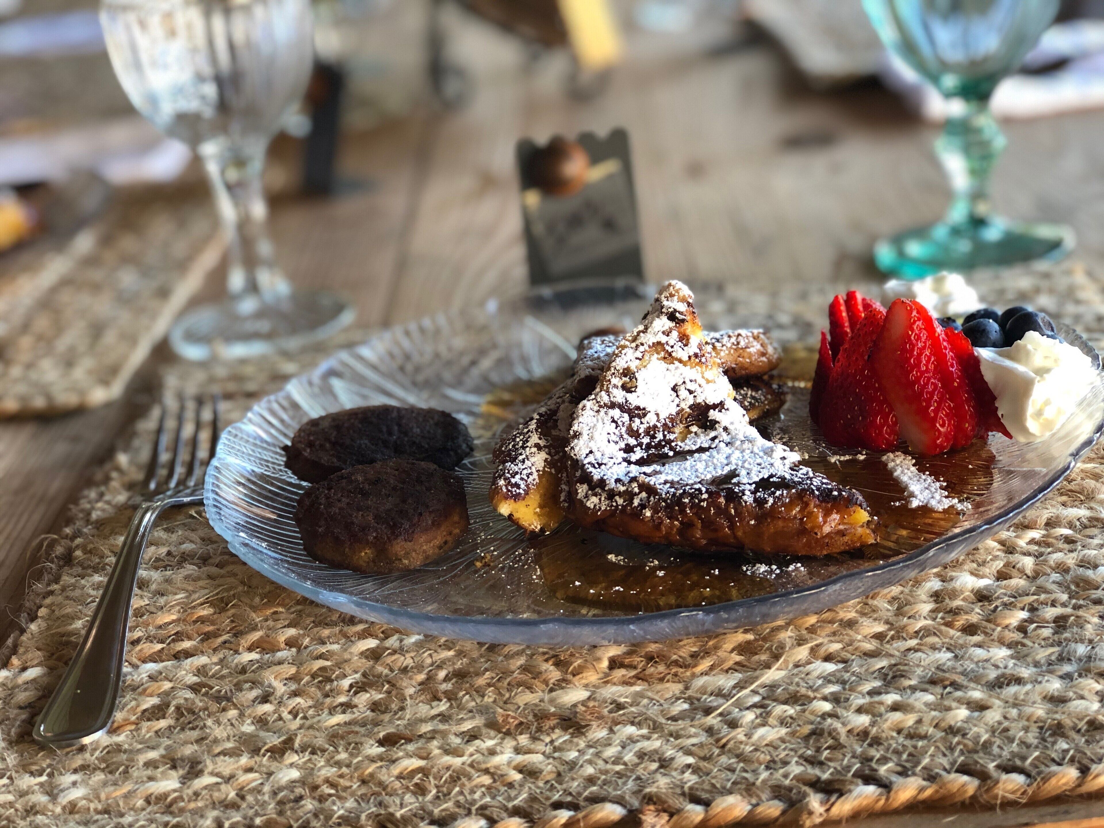 A plate with pastries, a glass of drink, and a fork on a woven placemat.