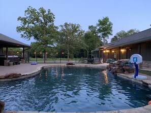 A swimming pool with a basketball hoop, surrounded by a wooden deck and stone features. - ElKen Retreat Experience: relax, rest, enjoy Suite 3  (Canton)