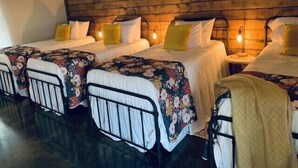 Habitación de hotel con dos camas individuales, cada una con una colcha estampada y cabecero. La habitación tiene un cabecero de madera y una mesita de noche con lámpara.