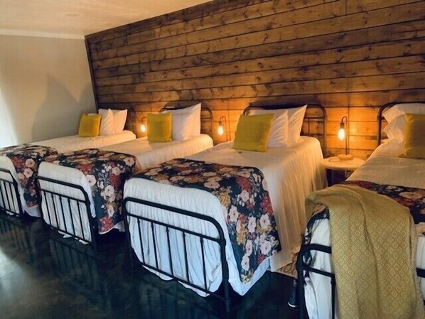 A hotel room with two single beds, each with a floral bedspread and a headboard. The room has a wooden headboard and a small bedside table with a lamp. - ElKen Retreat Experience: relax, rest, enjoy Suite 3  (Canton)