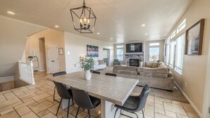 A spacious living area with a dining table, chairs, a fireplace, and a large TV.