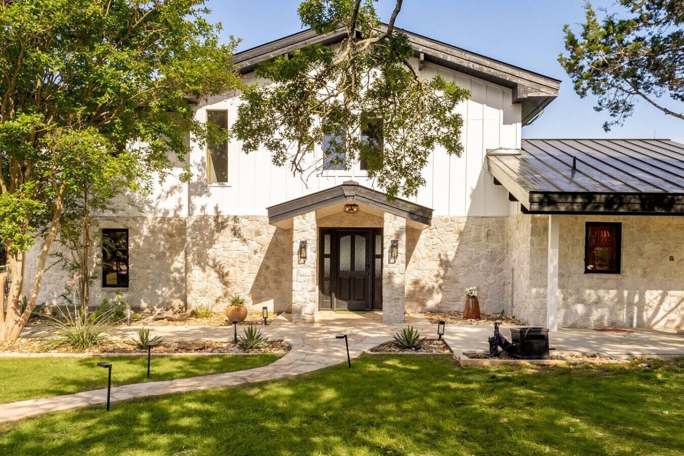 A two-story house with a stone facade, a dark front door, and a covered porch area.