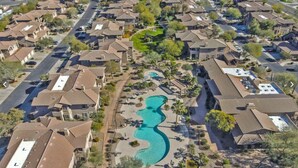 An aerial view of a residential area with houses, a winding pool, and a central green space. - Resort-like amenities and perfectly located Scottsdale condo (Scottsdale)