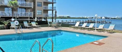 A swimming pool with lounge chairs and a view of a water body.