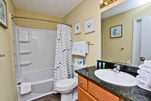 A bathroom with a bathtub, toilet, sink, and vanity. - Cabana Beach House (Gulf Shores)