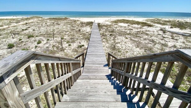 A wooden boardwalk leading to a beach with clear skies. - Cabana Beach House (Gulf Shores)