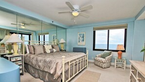 A bedroom with a bed, a chair, a desk, a mirror, and a window with a view. - Broadmoor 304 (Orange Beach)