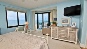 A bedroom with a bed, a dresser, a TV, and a balcony with a view of the ocean. - Broadmoor 304 (Orange Beach)