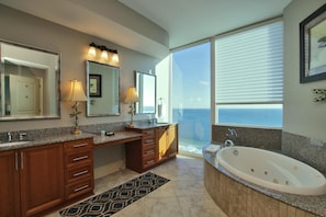 A modern bathroom with a large bathtub, dual sinks, and a large mirror.