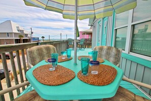 A turquoise outdoor dining area with woven placemats and striped umbrellas.