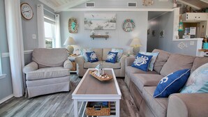 A cozy living room with two sofas, a coffee table, and decorative wall art. - Dream Catcher (Gulf Shores)