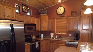 A kitchen with wooden cabinets, a stainless steel refrigerator, a microwave, a sink, and a clock on the wall. - FREE TORREON GOLF GREEN FEES  -  Designer Furnished Villa 3 night minimum     (Show Low)