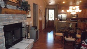 A spacious living room with a fireplace, a dining area, and a kitchen with wooden cabinets and a chandelier. - FREE TORREON GOLF GREEN FEES  -  Designer Furnished Villa 3 night minimum     (Show Low)