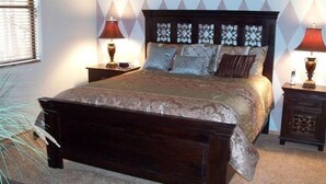 A bedroom with a large bed, two bedside tables with lamps, a decorative wall pattern, and a plant. - FREE TORREON GOLF GREEN FEES  -  Designer Furnished Villa 3 night minimum     (Show Low)