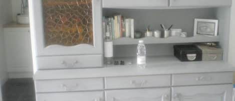 A white cabinet with a decorative glass panel, a water bottle, books, and a small framed picture.