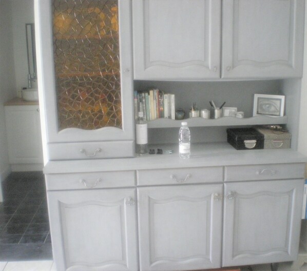 A white cabinet with a decorative glass panel, a water bottle, books, and a small framed picture. - 1 Bedroom Private vacation home in Audenge (Audenge)