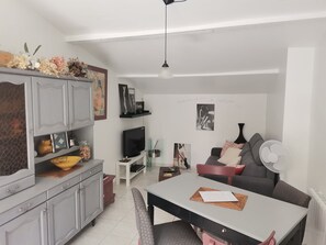 Una sala moderna con una mesa de comedor, sofá, televisor y objetos decorativos.