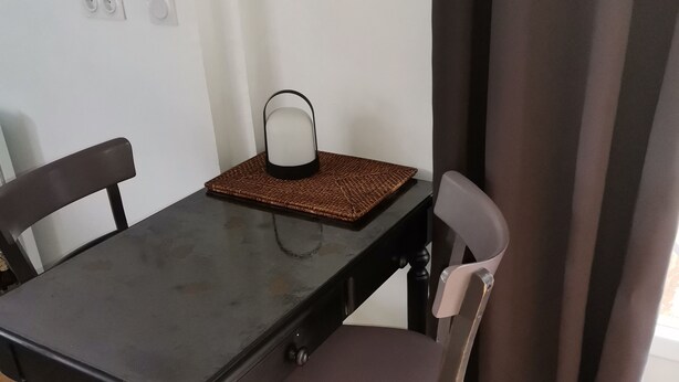 A dining table with two chairs, a woven placemat, and a wall-mounted light fixture.