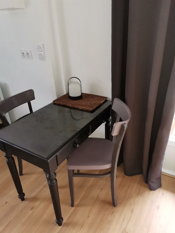 A dining table with two chairs, a woven placemat, and a wall-mounted light fixture. - STUDIO "house" with TERRACE at the foot of the cycle paths (Audenge)