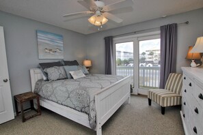 A bedroom with a bed, a ceiling fan, a window with curtains, a chair, and a dresser.