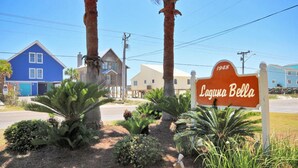 A sign for Laguna Bella with a year marker of 1948, surrounded by tropical plants and palm trees. - Laguna Bella B1 (Gulf Shores)
