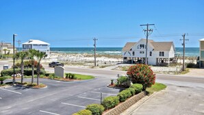 A coastal road with a beachside house, a parking lot, and a clear view of the ocean. - Laguna Bella B1 (Gulf Shores)