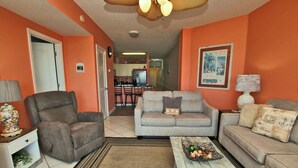 A living room with a gray sofa, a gray armchair, a coffee table with fruits, and a lamp. - Legacy 102 (Gulf Shores)