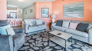 A living room with two grey sofas, a coffee table, and a floral rug. - Legacy 102 (Gulf Shores)