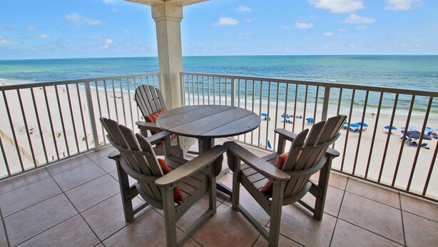 A covered outdoor seating area with a view of the beach and ocean.