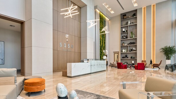 Eine moderne Lobby mit einer Rezeption, einer Sitzecke und einer Wand mit vertikalem Grünpflanzenwand.