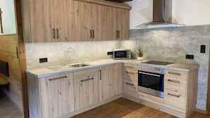 Une cuisine moderne avec des meubles en bois, un évier en acier inoxydable, un four à micro-ondes et un four traditionnel.