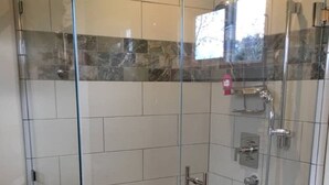 A glass-enclosed shower stall with a tiled floor, a handheld showerhead, and a wall-mounted faucet. - The Post Office Cabin, near Mercy Hotsprings. (Paicines)