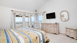 Une chambre à coucher avec un lit, une télévision, une commode et une chaise.