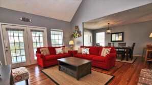 A spacious living room with a red sofa set, a coffee table, and a dining area with a wooden table and chairs. - Sunset Daze (Gulf Shores)