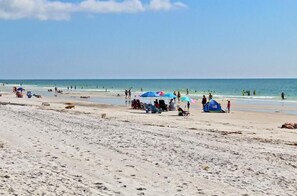 A beach with people, umbrellas, and a tent.