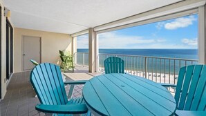 A balcony with a view of the ocean, featuring a table and chairs.