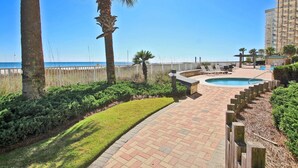 A pool area with a view of the ocean, surrounded by a wooden fence and palm trees.