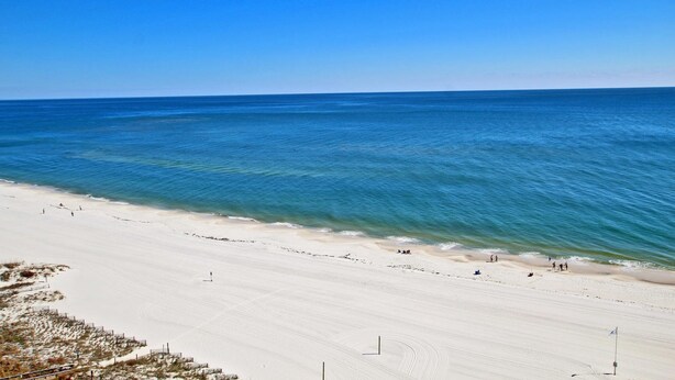 A beach with clear blue water and a sandy shore.