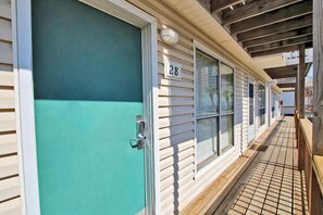 A row of mobile homes with a numbered door, a wooden deck, and a covered walkway. - Sand Dollar 28 (Gulf Shores)