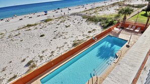 A pool adjacent to a beach with a clear view of the ocean. - Westwind 301 (Gulf Shores)