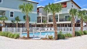 Ein Strandhotel mit mehrstöckigen Gebäuden, einem Swimmingpool und Palmen.