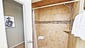 A shower with beige tiles and a showerhead. - Phoenix East 1201 (Orange Beach)