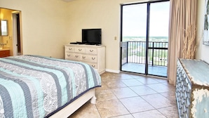 A hotel room with a bed, a dresser, a television, and a balcony with a view. - Phoenix East 1201 (Orange Beach)